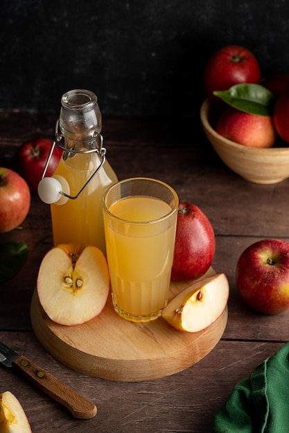 Boisson au jus de pomme avec des pommes rouges fraîches fond en bois sombre bakground