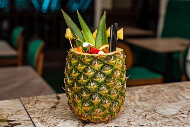 Une boisson au rhum cocktail alcoolisée tropicale aux fruits sucrés servie dans un ananas au bar