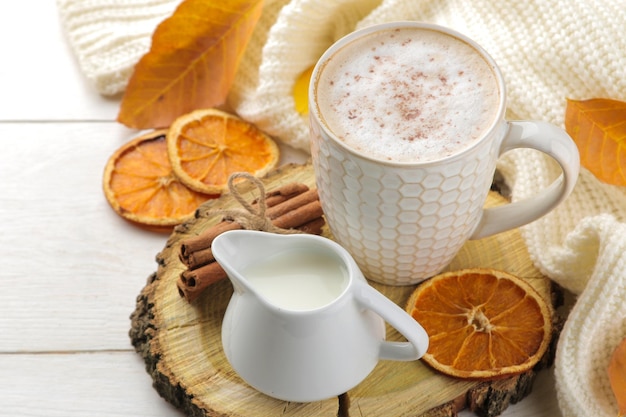 Boisson d'automne chaude café ou cacao avec des feuilles jaunes et des citrouilles décoratives sur une composition d'automne de table en bois blanc