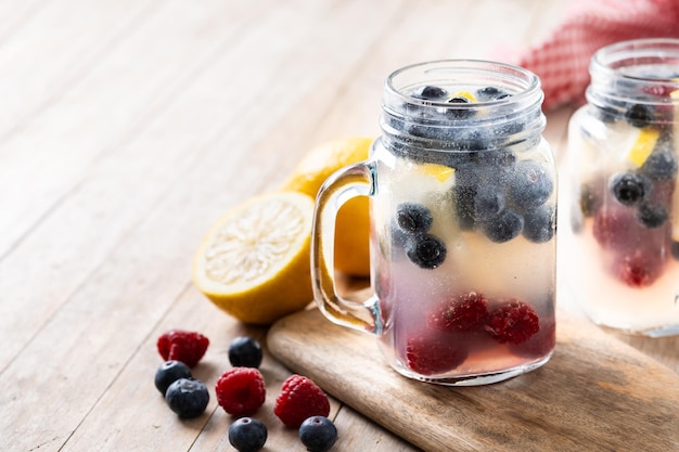 Boisson de baies fraîches avec des bleuets, des framboises et du citron sur une table en bois.