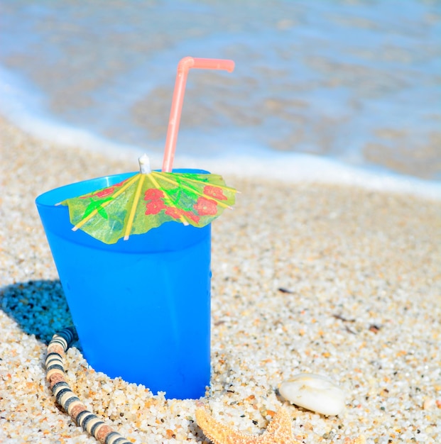 Boisson bleue avec coquillages et collier au bord de la mer