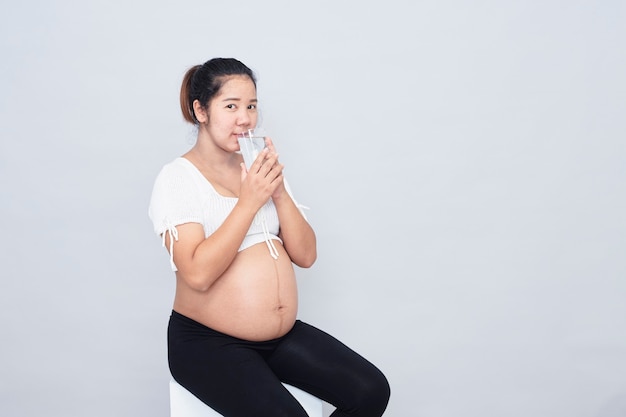 Boisson de calcium saine. Enceinte jeune femme asiatique assise boire du calcium sain. Enceinte jeune femme asiatique assise tenant un verre de lait