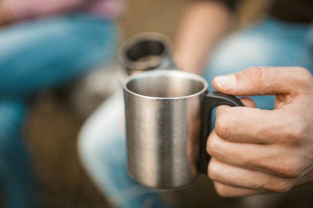 Boisson chaude dans la nature, main masculine tenant la tasse