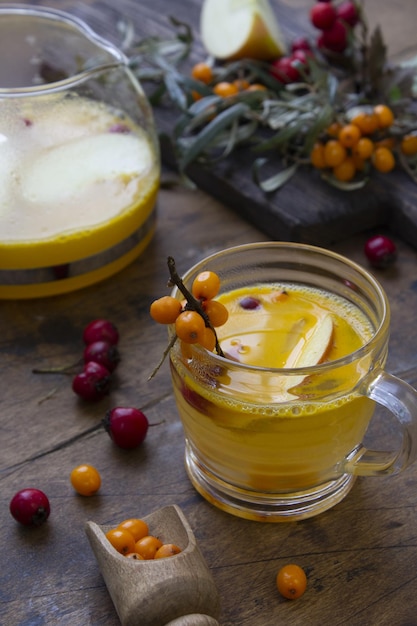 Boisson chaude d'hiver thé frais d'argousier avec pomme dans un verre sur une table en bois