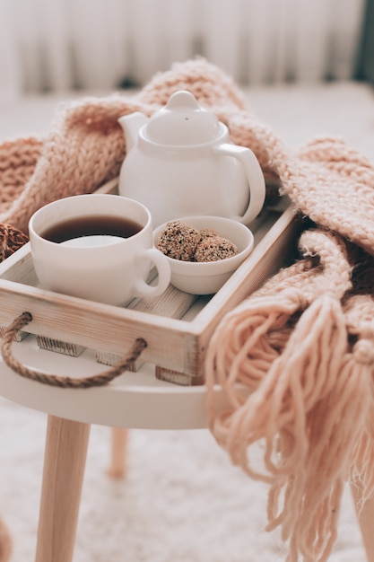 Boisson chaude et théière sur un plateau de service avec des vêtements en tricot.