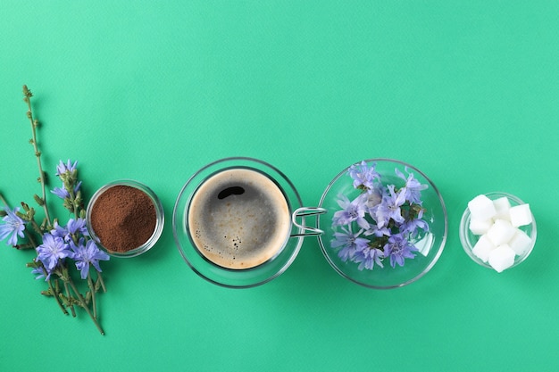 Boisson à La Chicorée Dans Une Tasse En Verre, Avec Du Concentré, Du Sucre Et Des Fleurs Sur Fond Vert. Boisson à Base De Plantes Saine, Substitut De Café, Vue De Dessus, Espace Pour Le Texte