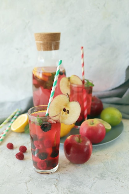 Boisson détox à base de pommes, de baies, de menthe et d'agrumes dans des verres et dans une carafe