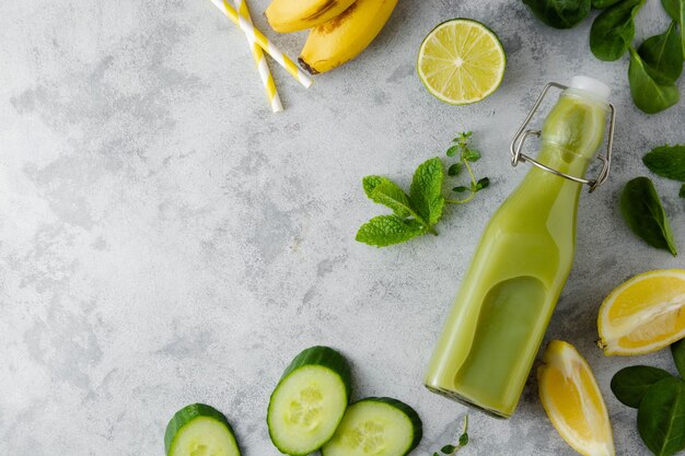 Boisson Détox Smoothie Vert Dans Une Bouteille En Verre Avec épinards Frais, Concombre, Banane Et Citron Vert. Espace De Copie, Vue De Dessus.