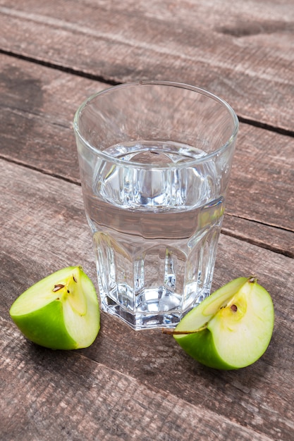 Boisson diététique de désintoxication avec des tranches de pomme dans de l'eau propre et une pomme fraîche sur une table en bois, gros plan