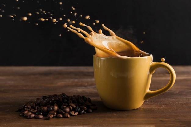 Photo une boisson éclabousse de la tasse près des grains de café