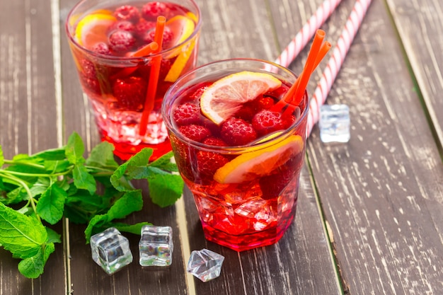 Boisson d'été aux framboises, citron vert et glace sur une vieille table en bois