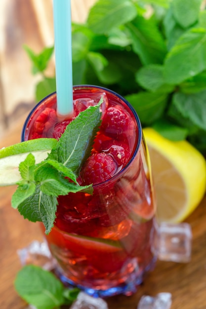 Boisson d&#39;été aux framboises, citron vert et glace sur une vieille table en bois