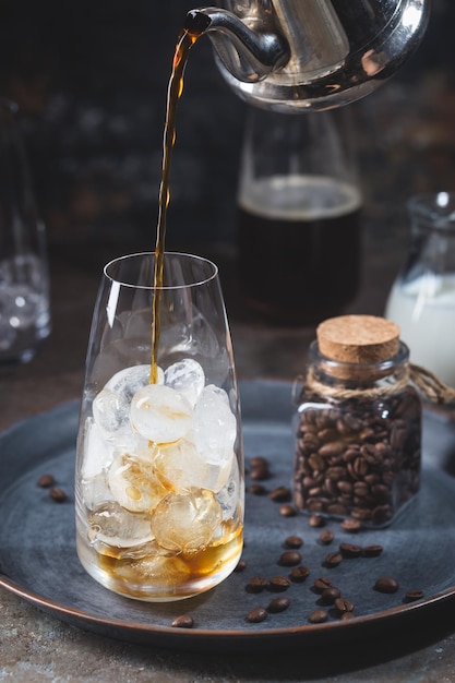 Boisson d'été froide au café glacé dans un grand verre avec du café et des grains de café sur fond de pierre.