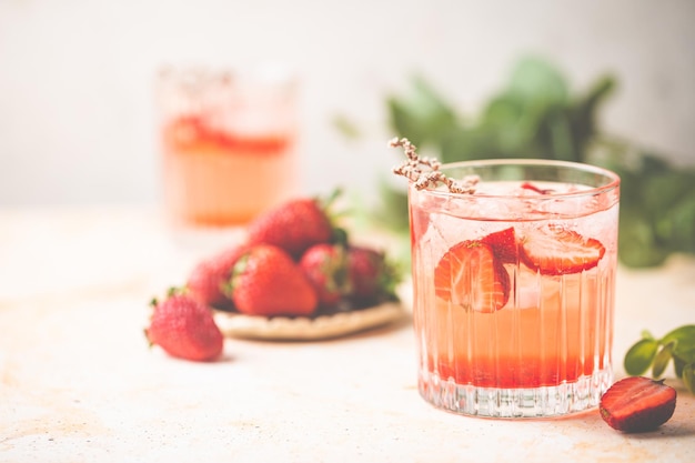 Boisson d'été rafraîchissante avec des tranches de fraise dans des verres sur fond blanc