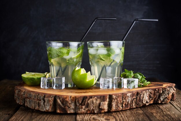 Boisson fraîche au citron vert, menthe et glace sur table en bois sur dark