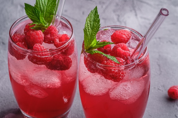 Boisson fraîche au jus de baies glacées à la menthe, limonade d'été aux framboises dans deux verres avec des pailles