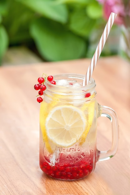 Boisson fraîche d'été pour étancher la soif de citron et de groseille avec des glaçons sur la table dans le jardin