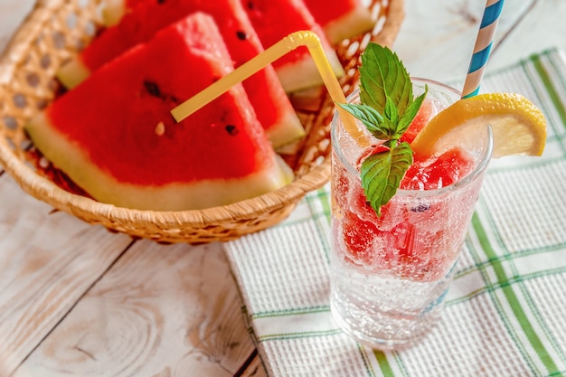 Boisson fraîche d'été avec des tranches de pastèque, menthe et citron sur un fond en bois,