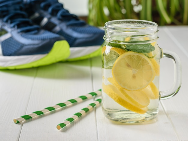 Boisson fraîchement préparée de citron et de menthe sur le fond des chaussures de sport.