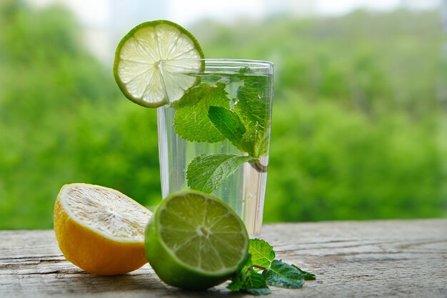 Une boisson froide à base de citron, de citron vert et de menthe dans une tasse en verre