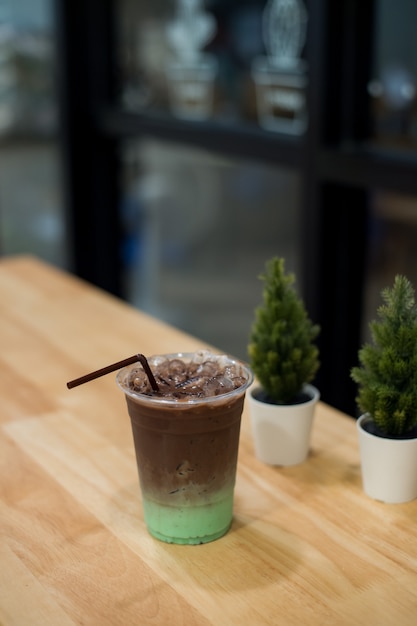 Boisson froide à la menthe et au chocolat dans un verre en plastique, posé sur une table en bois