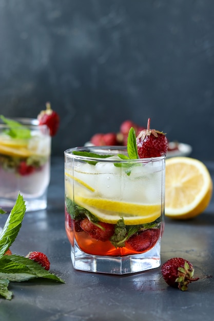 Boisson froide mojito aux fraises avec fraise, tranches de citron et menthe, photo verticale