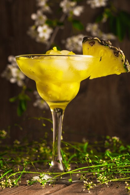 Photo boisson gazeuse aux fruits ananas avec de la glace sur une surface en bois avec des fleurs