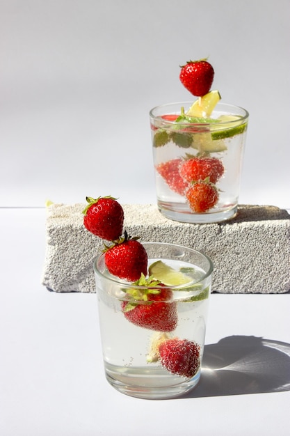 Photo boisson gazeuse avec des tranches de citron vert et des fraises dans des verres décorés de feuilles de menthe