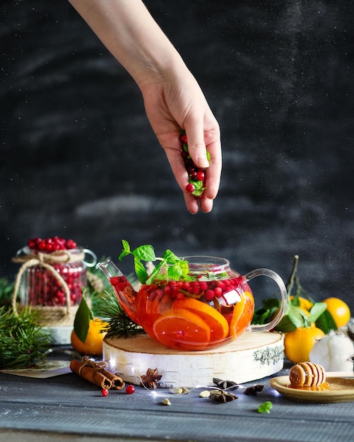 Boisson d'hiver Thé aux canneberges avec mandarines et menthe Une main de femme dans la photographie alimentaire