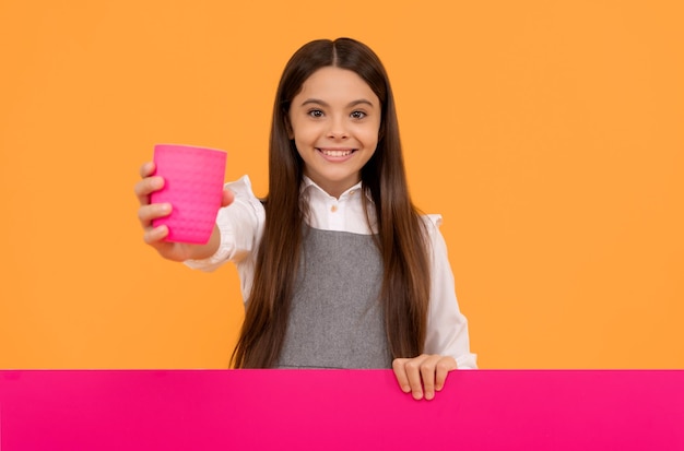 Boisson irrésistiblement rafraîchissante Un enfant heureux donne une tasse en plastique tenant un panneau publicitaire De l'eau potable ou du jus Espace de copie publicitaire pour les boissons