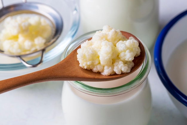 Boisson lactée fermentée au kéfir avec des grains de kéfir. Le kéfir fait maison se tient dans un verre, à côté des grains de kéfir et du lait