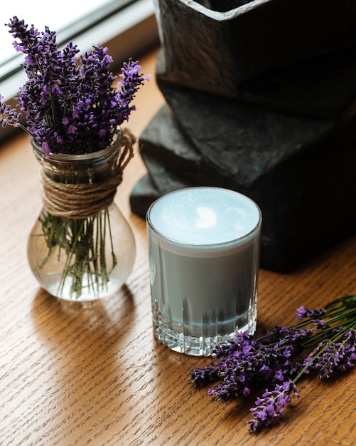 Boisson latte lavande bleue dans un verre sur la table avec des fleurs