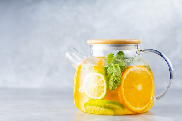 Photo boisson de limonade detox d'eau, de citron, d'orange et de feuilles de menthe dans une théière transparente