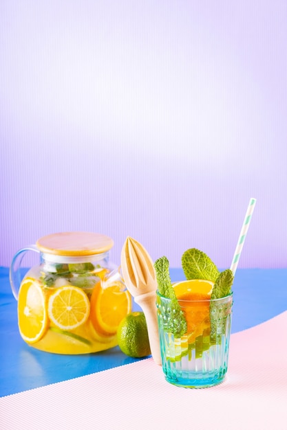 Boisson de limonade d'eau, de citron, d'orange et de feuilles de menthe sur fond multicolore