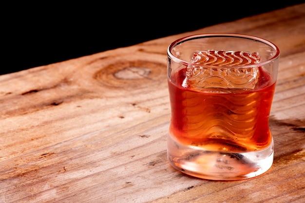 Photo boisson negroni avec glace à croûte professionnelle ondulée sur fond sombre de table en bois