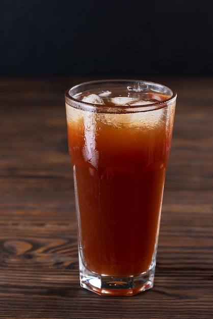 Boisson non alcoolisée avec de la glace dans un grand verre sur une table en bois marron