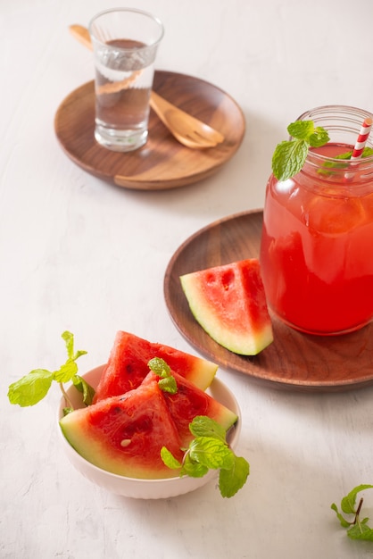 Boisson de pastèque en verre avec des tranches de pastèque sur surface blanche