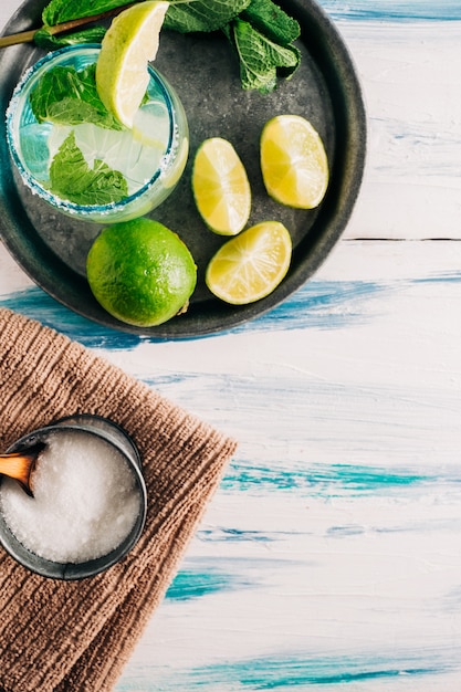 Photo boisson rafraîchissante au citron vert. mojito maison sur une table en bois d'été entourée de limes, de menthe poivrée et de sucre. copyspace