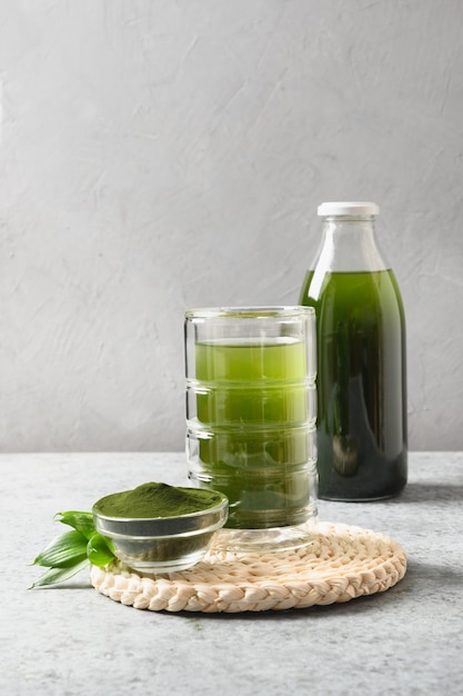 Boisson saine chlorella en verre sur fond gris.