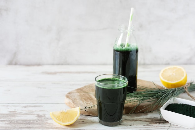 Boisson à la spiruline avec de la poudre d'algues citron et spiruline sur une table en bois blanc