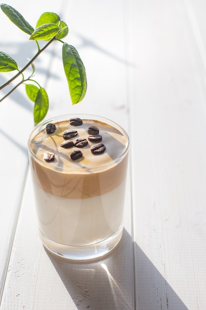 Boisson traditionnelle coréenne café Dalgona dans un verre avec des grains de café sur un des tableaux blancs