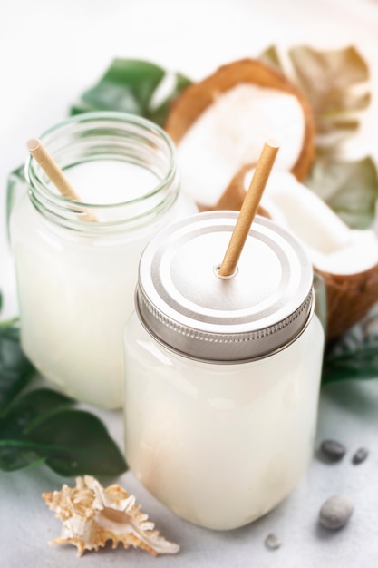 Boisson tropicale d'eau de coco dans un bocal en verre avec poignée sur fond clair avec espace de copie