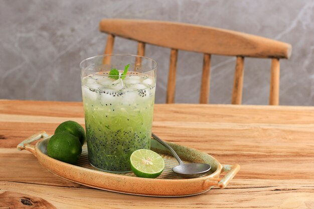 Photo boisson végétarienne indonésienne es timun serut à base de concombre râpé, de jus de citron vert et de graines de basilic, servi sur un verre transparent sur une table en bois