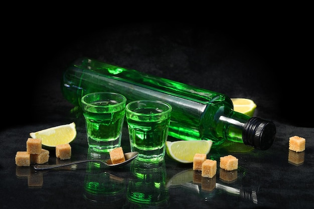 boisson verte d'absinthe sur le fond noir avec du sucre et de la chaux