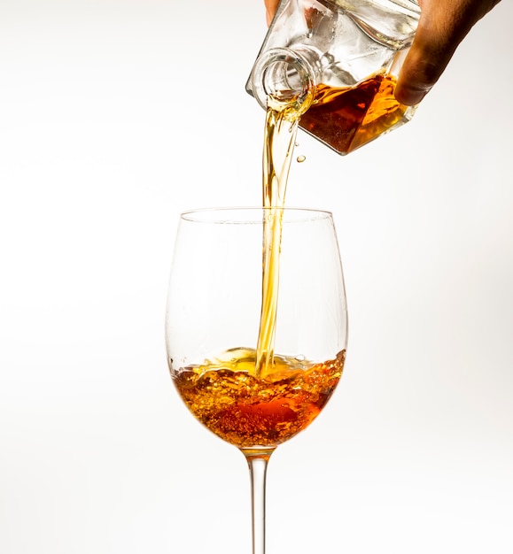Des boissons alcoolisées sont versées dans un verre de carafe sur un fond clair