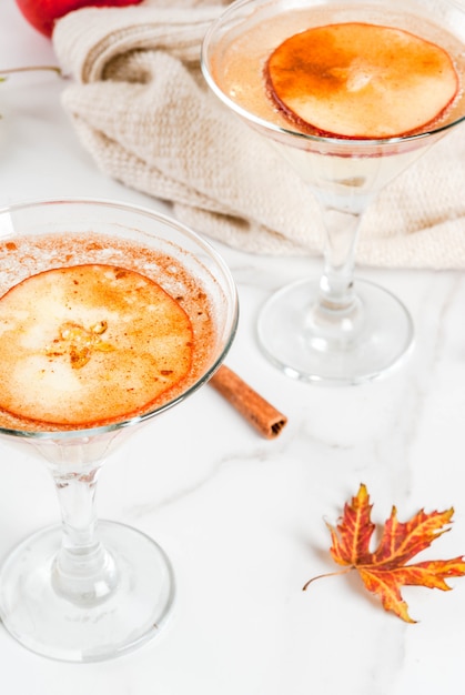 Boissons d'automne et d'hiver Margarita au cidre et à la pomme avec garniture à la cannelle et aux pommes sur une table en marbre blanc