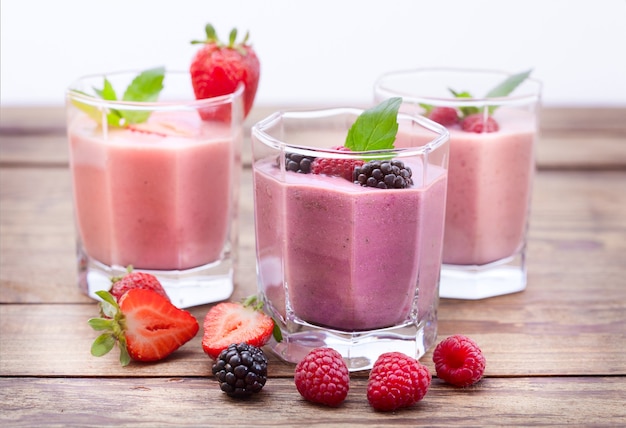 Boissons aux baies et fraises, mûres, framboises sur table en bois.