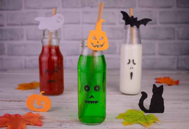 Boissons en bouteilles aux visages de monstres. Visage Jack-o-lanterne sur verre. Boissons d'Halloween.