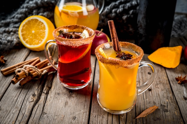 Boissons et cocktails traditionnels d'automne et d'hiver. Sangria épicée chaude d'automne blanc et rouge avec anis, cannelle, pomme, orange, vin. Dans des tasses en verre, vieille table en bois rustique. Espace de copie de mise au point sélective