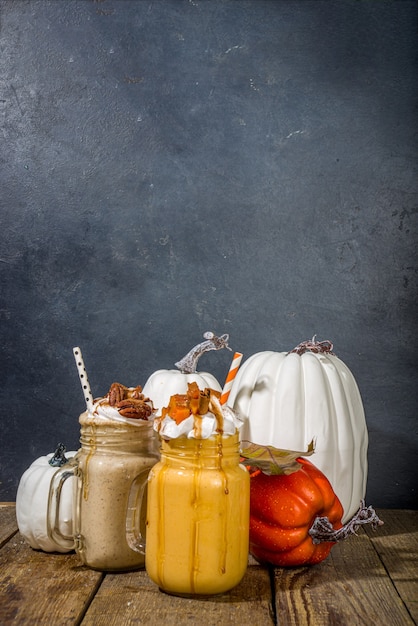 Boissons fouettées aux pommes, à la citrouille et aux noix de pécan. Ensemble de cocktails traditionnels de saveur de gâteau de cuisson d'automne, sur l'espace de copie de fond en bois foncé